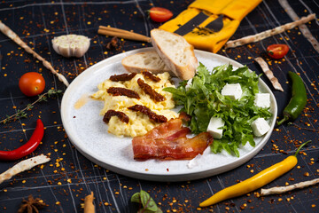 Breakfast with scrambled eggs, bacon and vegetable salad