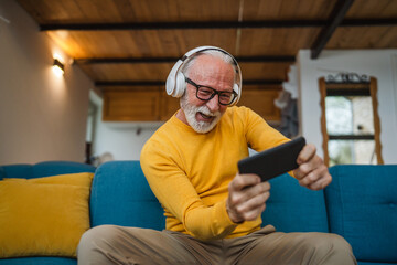 senior old man sit at home play video games on smartphone mobile phone