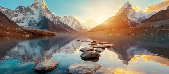 mountains with illuminated peaks, stones in mountain lake, reflection, blue sky and yellow sunlight - obrazy, fototapety, plakaty