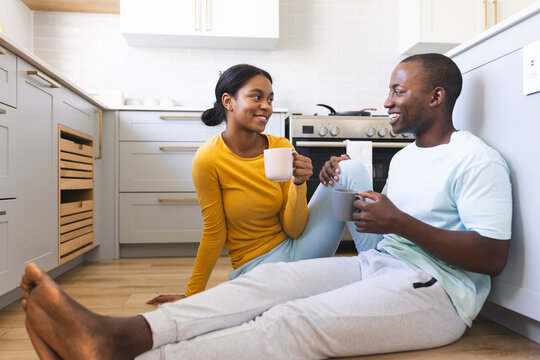 A diverse couple enjoys a cup of coffee in the kitchen at home