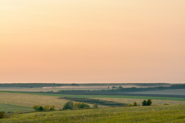 harvesters in in the distant fields in the evening