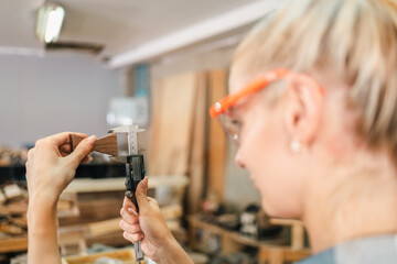 In the carpenter's shop, a professional woman crafts wooden furniture, using tools with skill in her woodwork occupation, showcasing industry prowess.