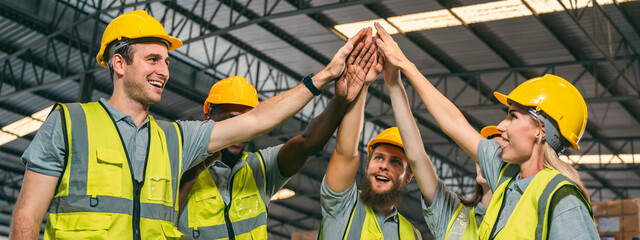 In a factory setting, a team of engineers and foremen emphasize safety and teamwork during a...