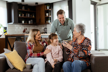 Joyous Family Celebrating Grandmothers Birthday With Cake in a Cozy Living Room - 763447103