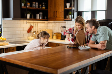 Joyful Family Enjoying Homemade Chocolate Cake in Cozy Kitchen - 763447121