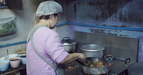 A woman is cooking in a kitchen with a blue wall