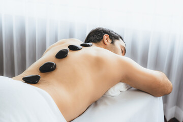Hot stone massage at spa salon in luxury resort with day light serenity ambient, blissful man...