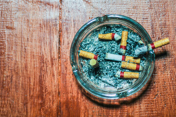 Ashtray full of cigarette butts on wooden floor