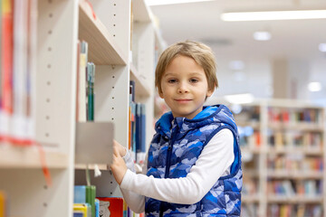 Smart child, school boy, educating himself in a library, borrowing books