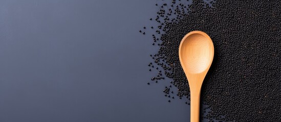 A wooden spoon filled with black sesame seeds on a dark surface