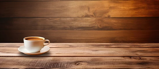 Fotobehang A cup of coffee on a wooden table with a rustic backdrop © Ilgun