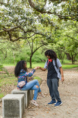 Vertical image of a couple of friends meeting in a park on a summer day. 