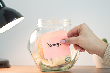 Female putting paper with inscription Savings on jar with euro money. Saving money, savings for education, purchase of house or car