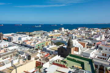 Fototapeta premium Freighter in the sea with roofs of a city in the foreground