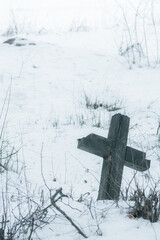 Wooden cross at abandoned cemetery in winter