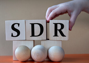 A child's hand places a large cube next to other cubes. SDR acronym concept