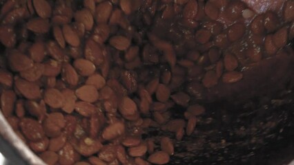 Candied and roasted almonds cooked with hot brown sugar.  Healthy sweet food. Cooking dessert snack close-up. Fried almond in sugar, production of sugared nuts. Mixing machine mealting food ingredient