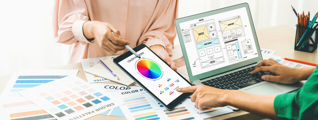 Cropped image of interior designer presents color from color swatches while laptop displayed...