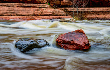 Water rushes by gray and red boulders in Oak Creek at Slide Rock State Park near Sedona Arizona - 763484179