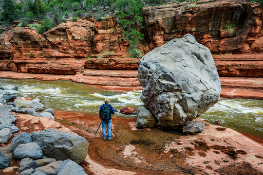 A photographer stands next to a giant gray boulder in Oak Creek Canyon near Sedona Arizona