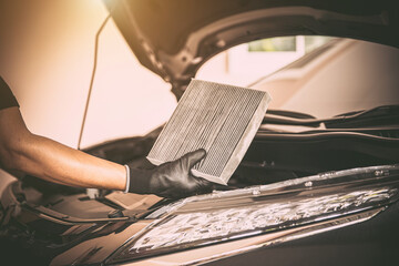 Auto mechanic checking, cleaning and replacing car air filter. Concept of car care service...