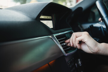 Woman adjusting an air grille on the vehicle dashboard.