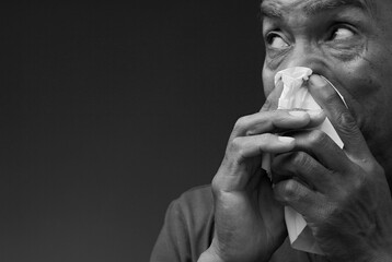 catching the cold and flu man blowing nose after catching a cold with grey background with people...