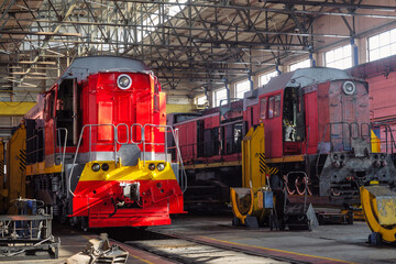 Red traction locomotives on serviced at a repair depot. Locomotive on fixed jacking units.