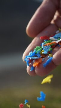 small pieces of plastic close up vertical video. primary and secondary microplastics. small plastic pellets in human hands. soil contamination, marine plastic pollution, environment, ecology, earth
