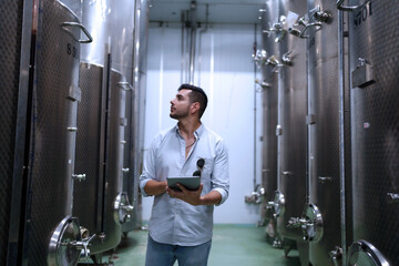 Winemaker working in modern large winery factory liquor drink industry quality and fermentation monitor.