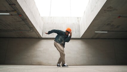 Stylish happy hipster perform break dance or freestyle foot step in building. Professional break...