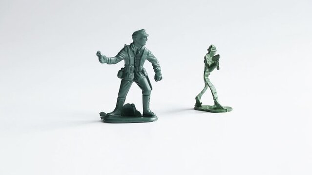 Female hand arranging green plastic soldiers on white