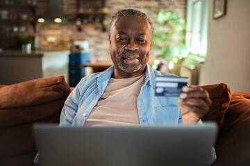 Senior man using credit card on laptop at home