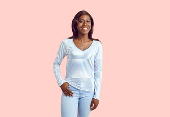 Portrait of happy smiling young african american woman standing in casual clothes with one hand in...
