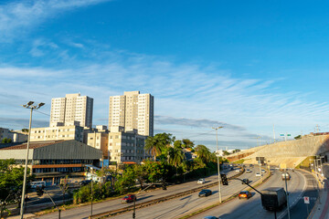 Naklejka premium Car traffic and trucks on an important avenue of the city of Belo Horizonte. Buildings, houses and highway. Blue sky with clouds. Trees. Power Posts. horizontal.