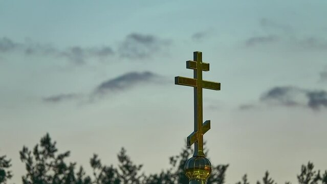 An Orthodox cross on the chapel dome against the background of the evening sky with clouds.