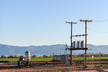 A wide view of an electric vertical turbine pump for agricultural irrigation next to power lines...