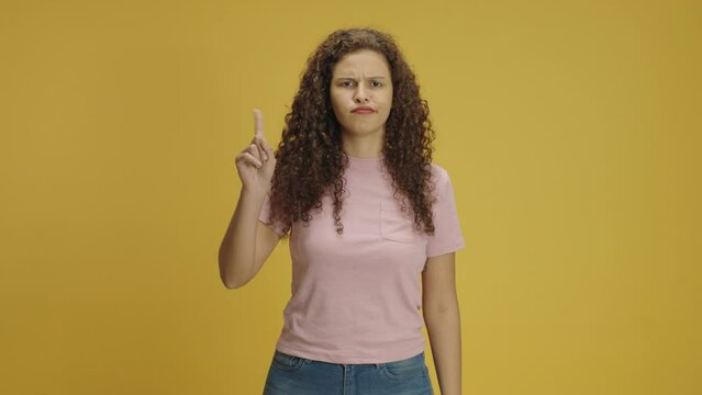 Young confident mixed race woman in pink t-shirt look camera pointing fingers himself ask say who me no thanks i do not need it isolated on yellow color background in studio
