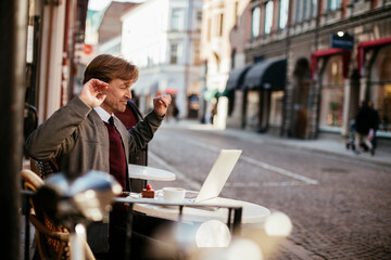 Mature man using a laptop while enjoying coffee in an outdoor cafe