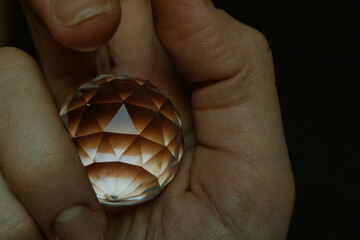 A round brown crystal ball, sphere in human hand close up. A transparent glass globe for spiritual...