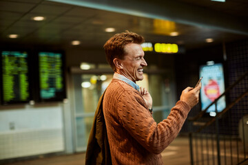 Mature man using a smart phone while waiting at a train station