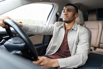  Portrait of a serious african american man driving a car with a beige interior