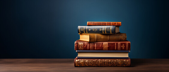 Stack of antique books on a wooden table against a dark blue background.Classic literature and reading concept. Banner for World Book Day event with copy space.  
