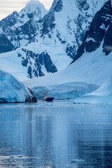 Expedition cruise ship passing through Lemaire channel in Antarctica at sunrise
