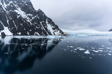 Expedition cruise ship passing through Lemaire channel in Antarctica at sunrise