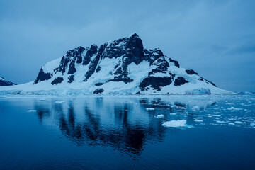 Expedition cruise ship passing through Lemaire channel in Antarctica at sunrise