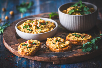 Hummus, chickpea puree in a bowl and on toasted bread slices