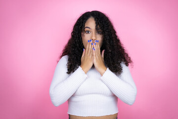 African american woman wearing casual sweater over pink background hocked covering mouth with hands for mistake. secret concept.