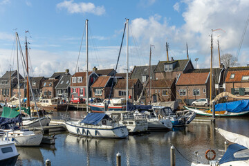 Spakenburg, the Netherlands. 25 February 2024. A harbor with boats and typical Spakenburg houses in the background on a cloudy day. - obrazy, fototapety, plakaty