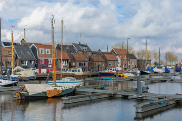 Spakenburg, the Netherlands. 25 February 2024. A harbor with boats and typical Spakenburg houses in the background on a cloudy day.